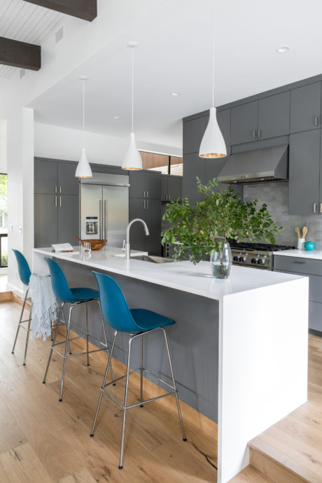 Modern kitchen with sleek gray cabinets, white countertop, and pendant lighting.