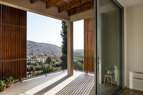 A spacious balcony with wooden beams and railing, offering a scenic countryside view.