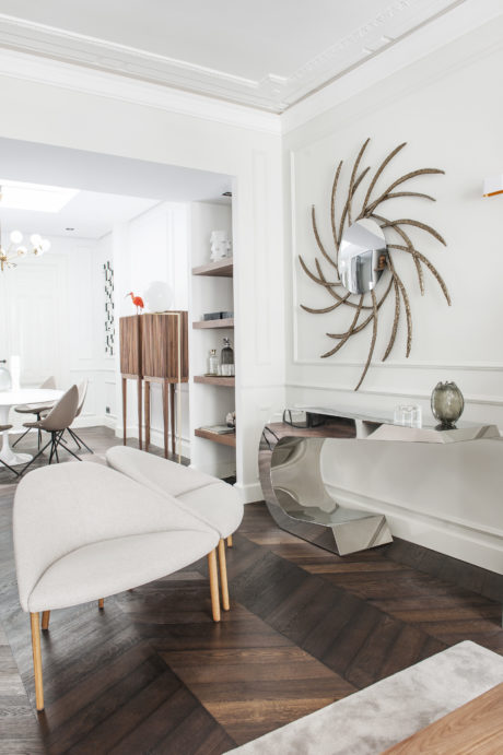 Elegant living room with modern furniture, decorative wall art, and a wood-paneled floor.