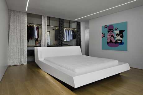 Modern bedroom with minimalist white bed frame, built-in closet, and vibrant abstract artwork.