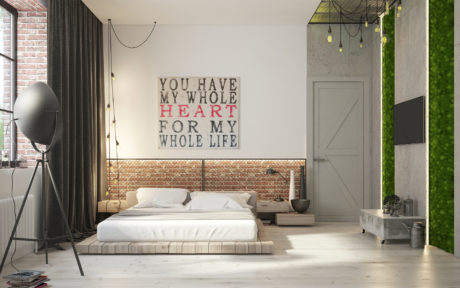 Spacious industrial-style bedroom with brick wall, hanging lights, and motivational wall art.