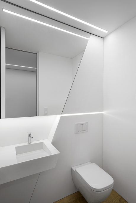 Sleek, minimalist bathroom with recessed lighting, floating vanity, and seamless surfaces.