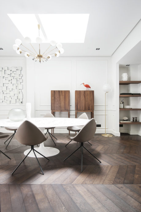 Modern, minimalist dining room with sleek furniture, wood floors, and a striking light fixture.