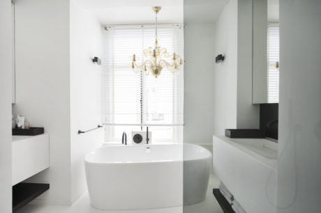 Elegant contemporary bathroom with freestanding tub, chandelier, and minimalist vanity.