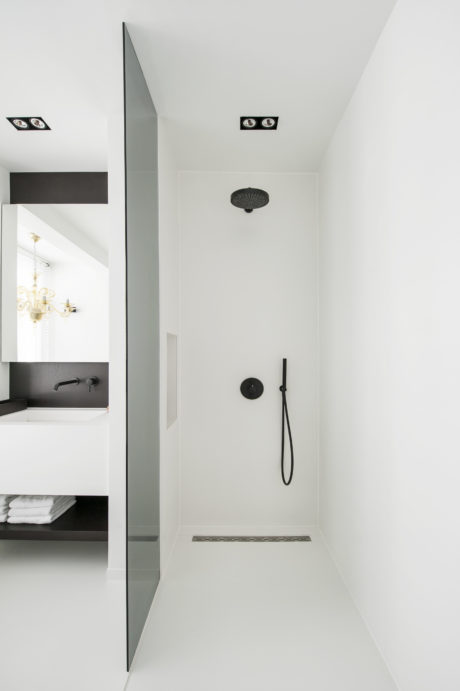 Minimalist bathroom design featuring sleek black fixtures, recessed lighting, and a frameless glass shower.