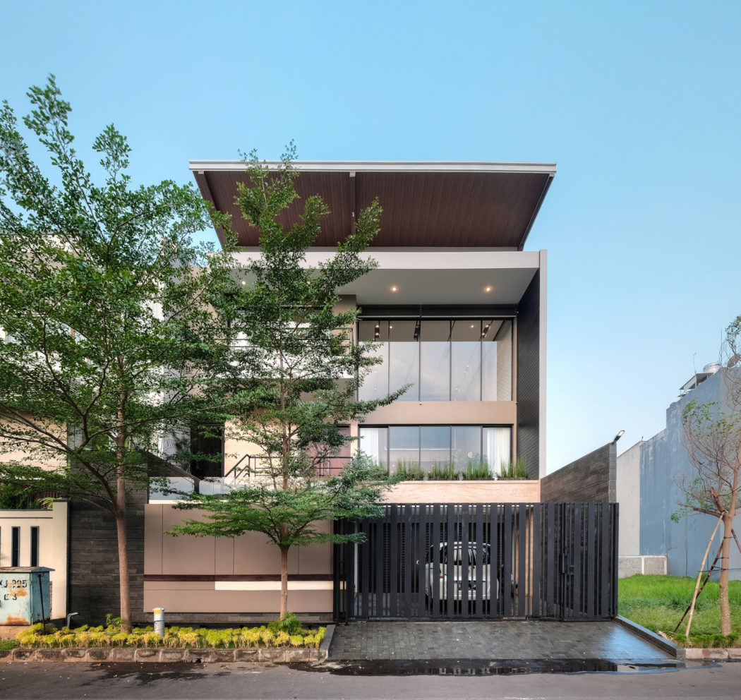 Modern three-story building with wooden accents, glass facade, and landscaped entrance.