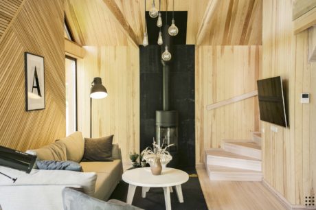 A cozy cabin interior with wooden walls, a modern fireplace, and stylish pendant lights.