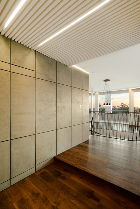 Sleek, modern interior with textured concrete walls, wooden flooring, and a minimalist overhead lighting fixture.
