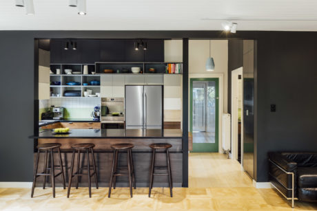 Modern kitchen with sleek black cabinets, wood countertops, and stainless steel appliances.