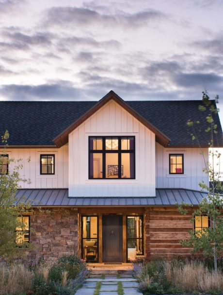 Rustic cabin-style home with mixed wood and stone facade against a cloudy twilight