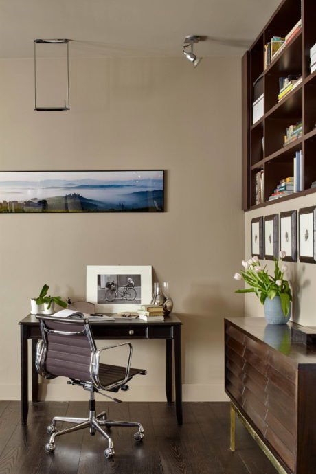 Cozy home office with dark wood furniture, shelves, and landscape artwork.