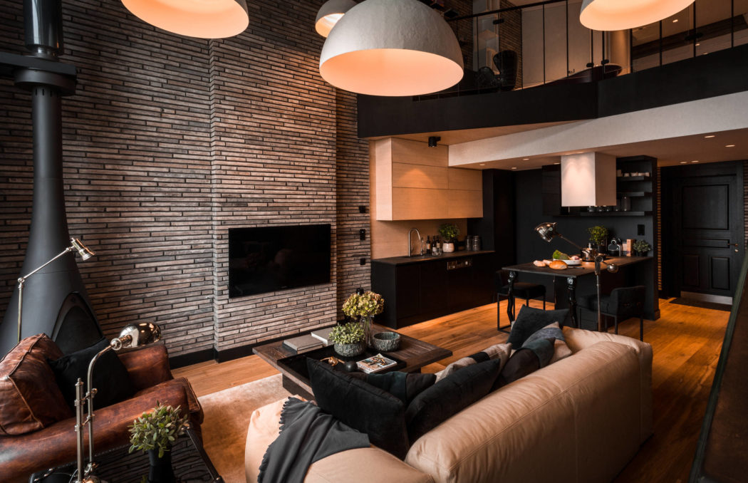 Cozy living room with brick walls, modern lighting, and sleek kitchen design.