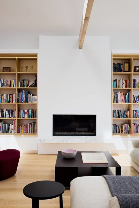 Modern living room with a fireplace, bookshelves, and minimalist furniture.