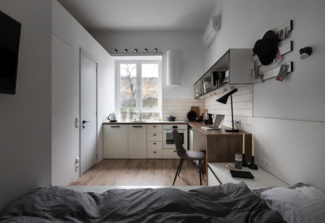 A modern and minimalist kitchen-living space with sleek cabinets, subway tiles, and wood accents.