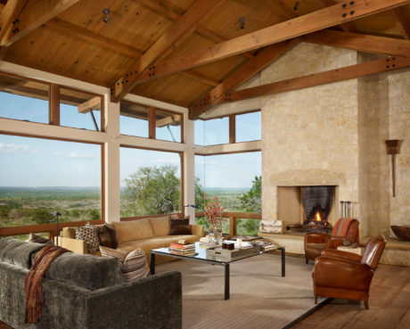 Rustic living room with exposed wooden beams and large windows showcasing a view.