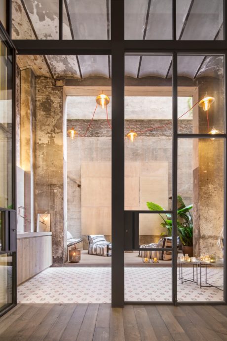 Rustic industrial-inspired interior with arched windows, pendant lights, and patterned flooring.