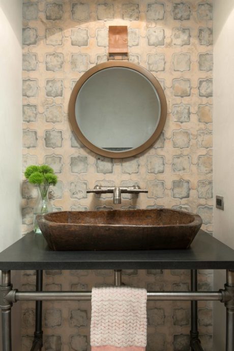 Rustic bathroom vanity with a stone vessel sink, industrial pipes, and round