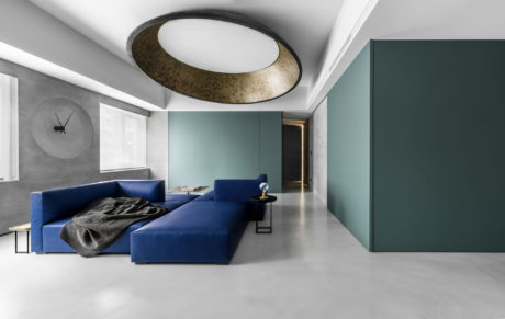 Contemporary living room with navy blue sectional, concrete floors, and a unique circular ceiling light fixture.
