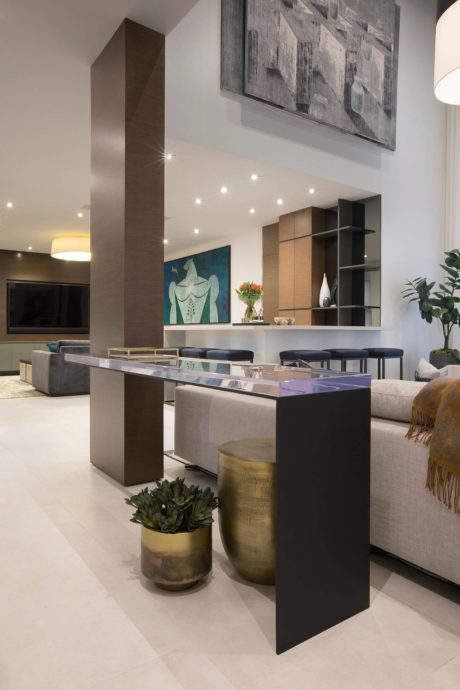 Sleek modern living room with abstract artwork, built-in shelving, and glass-topped coffee table.