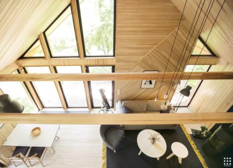 Spacious A-frame structure with high ceilings, large windows, and exposed wooden beams.