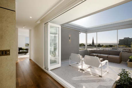 Spacious, modern living room with large windows offering scenic city views and elegant furniture.