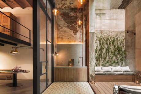 Rustic industrial interior with exposed brick walls, modern furnishings, and lush greenery.