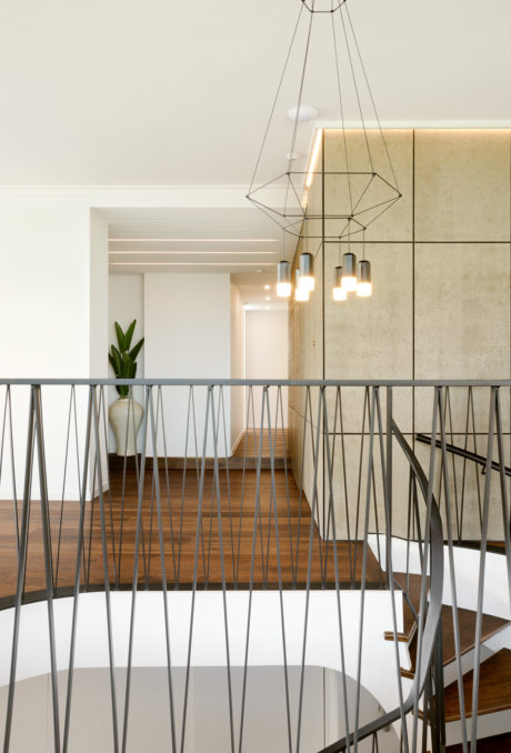 Modern staircase with geometric metal railings and a geometric pendant light fixture.