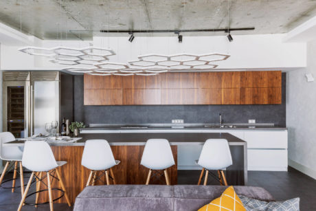 Sleek modern kitchen with wood cabinetry, concrete ceilings, and stylish lighting fixtures.