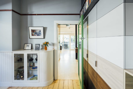 A modern hallway with white walls, wooden floors, and built-in cabinets showcasing décor.