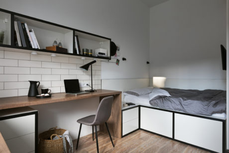 Well-designed modern bedroom with white subway tile, wooden desk, and sleek metal frame bed.