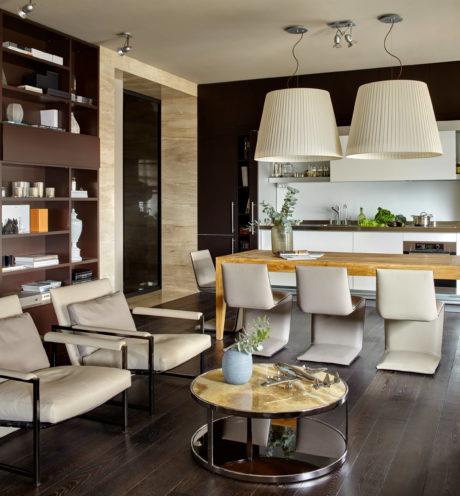 Sophisticated open-plan living with sleek shelving, warm wood table, and modern lighting.