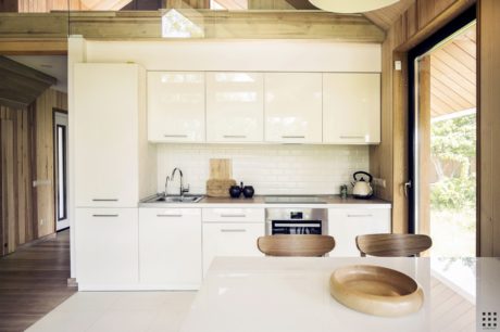 Rustic wooden cabin interior with modern white kitchen cabinetry and wooden accents.