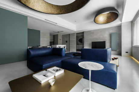 Luxurious living room with sleek navy blue sofas, marble coffee table, and unique pendant lights.