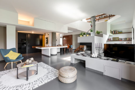 Minimalist open-concept living room with monochrome palette, sleek furniture, and elegant decor.