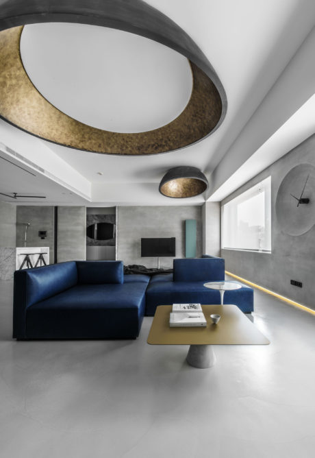 A modern, minimalist living room with a large, curved, backlit ceiling feature.