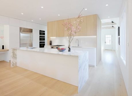 Bright minimalist kitchen with marble island and light wood cabinets.