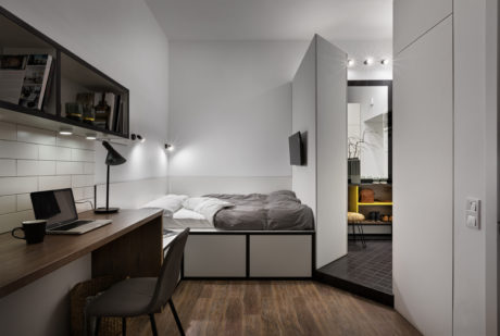 Cozy studio apartment with minimalist design, wooden flooring, and integrated storage space.