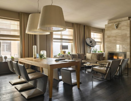 A cozy living room with a wooden dining table, plush seating, and large pendant lamps.