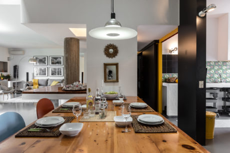 Modern open-plan dining area with wooden table, pendants, and eclectic decor.