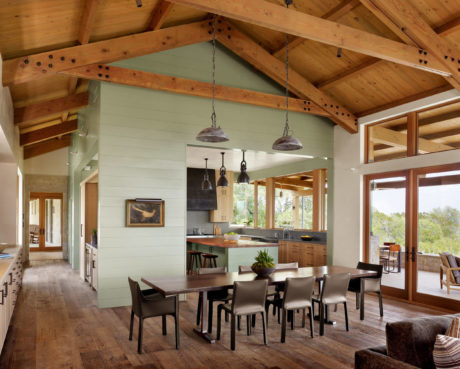 Rustic dining area with exposed wooden beams and a green accent wall.