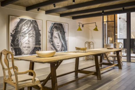 Rustic wooden beams, bench-style dining table, artwork featuring abstract faces.