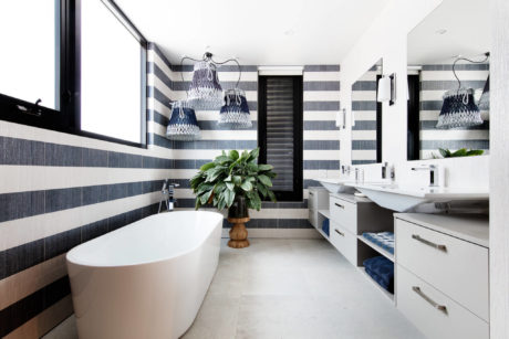 Spacious bathroom with striking monochrome striped walls, freestanding tub, and modern vanity.