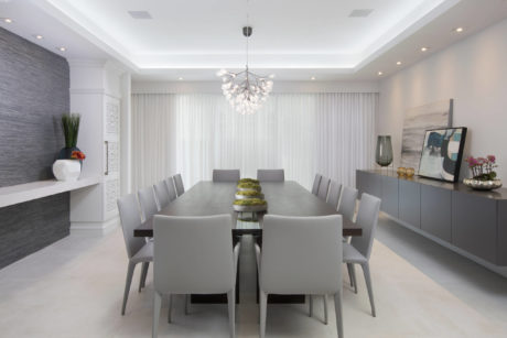Elegant modern dining room with sleek gray furniture, chandelier, and art pieces.