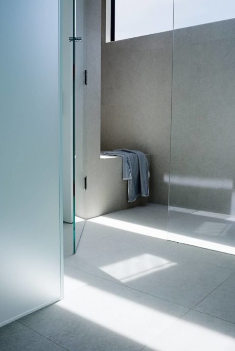Minimalist bathroom with glass door and natural light.