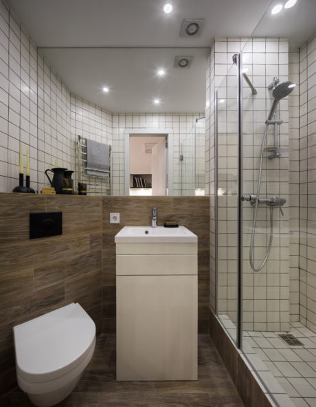 Modern bathroom with tiled walls, wooden vanity, and minimalist fixtures.