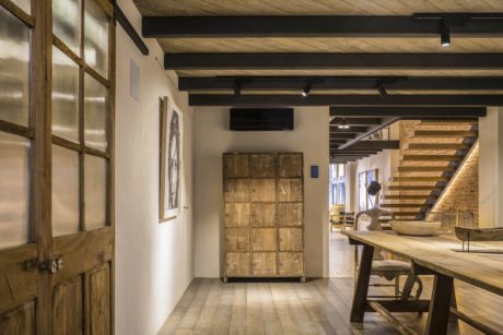 Rustic, industrial-inspired interior with exposed wooden beams, stairs, and wooden furniture.