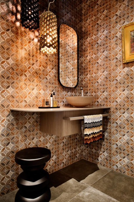 Intricate tiled wall patterns, recessed lighting, and a modern vanity with decorative towels.