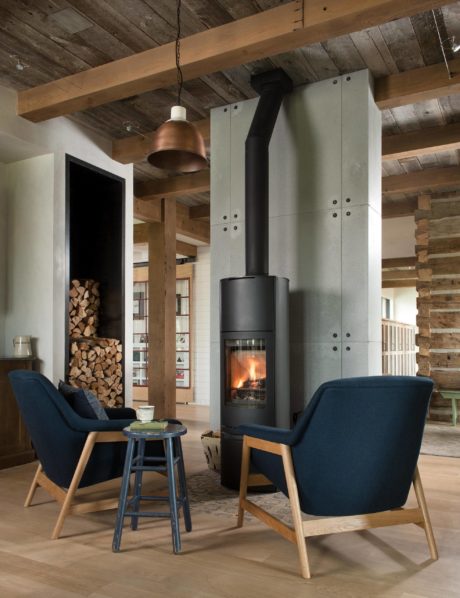 Rustic room with wood beams, modern fireplace, and navy armchairs