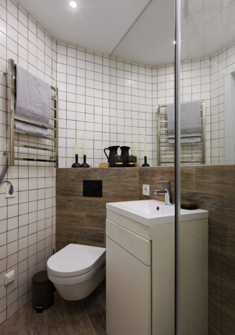 A modern bathroom with white tiles, wooden accents, and a simple vanity unit.
