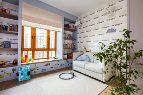 A cozy children's room with colorful wallpaper, built-in shelves, and a plush sofa.